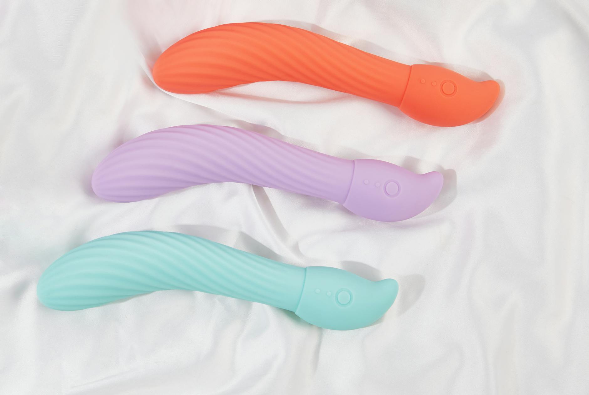 A sleek teal vibrator on soft white silk fabric, representing intimate reconnection and pleasure.