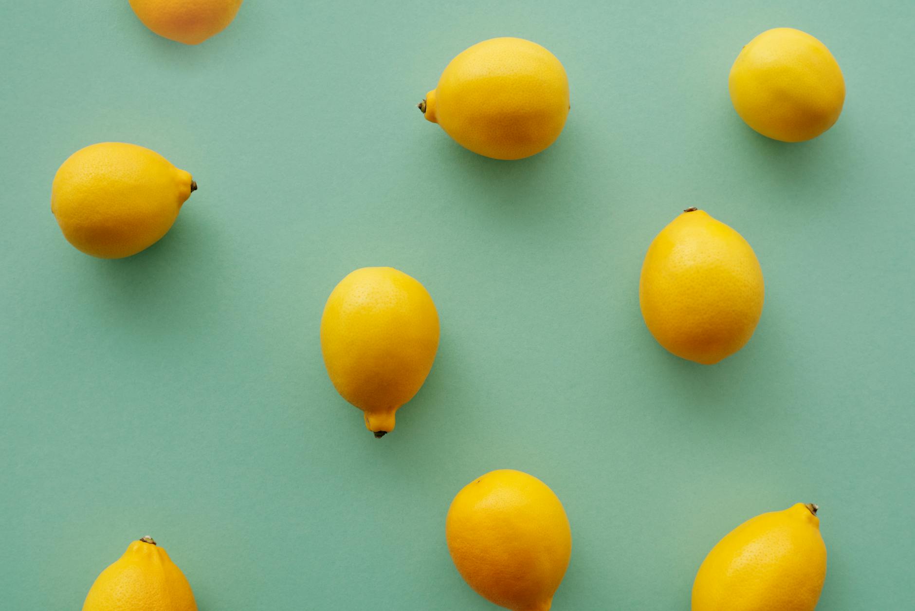 Bright yellow lemons arranged on a pastel background, symbolizing freshness and sensation