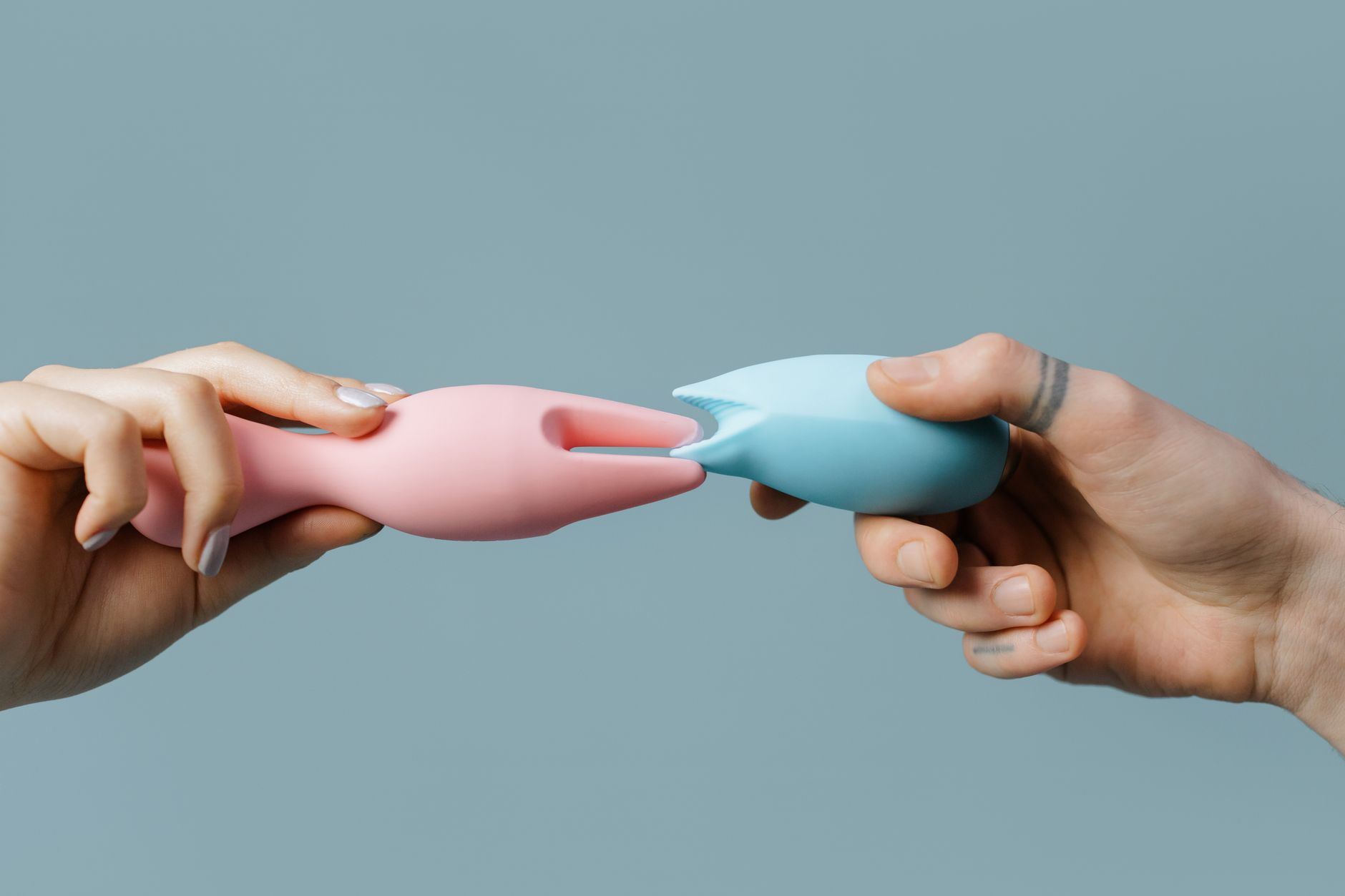 Two hands holding colorful silicone vibrators, symbolizing partnered exploration and shared pleasure